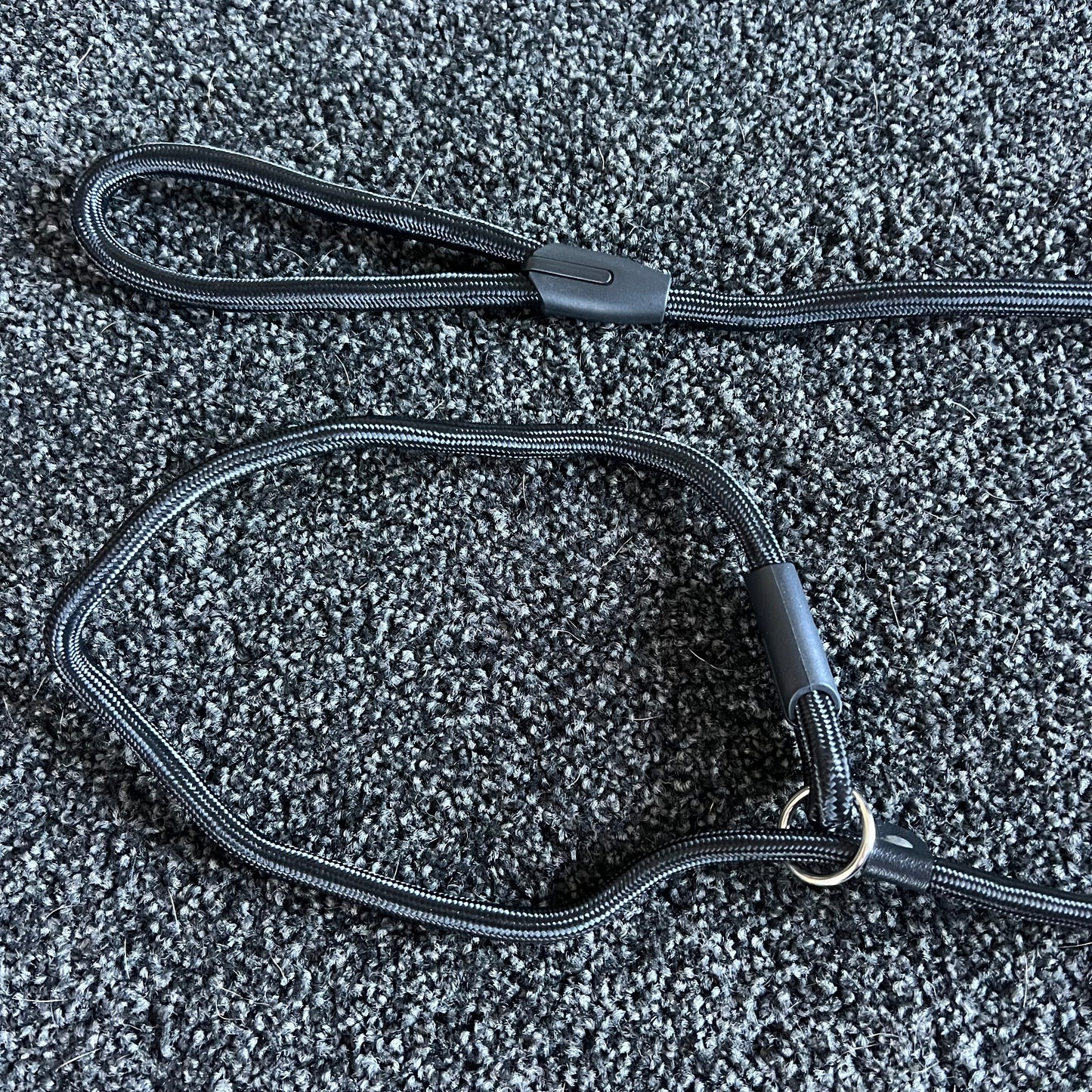 Black dog leash on a textured gray surface