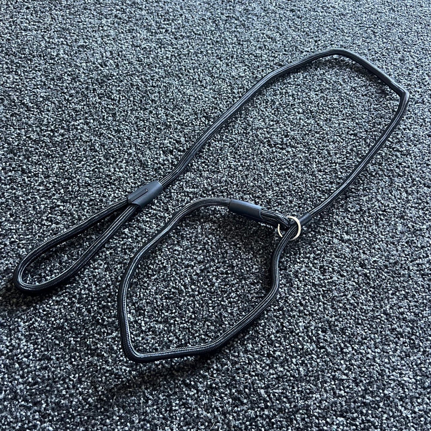 Black dog leash on a textured gray surface