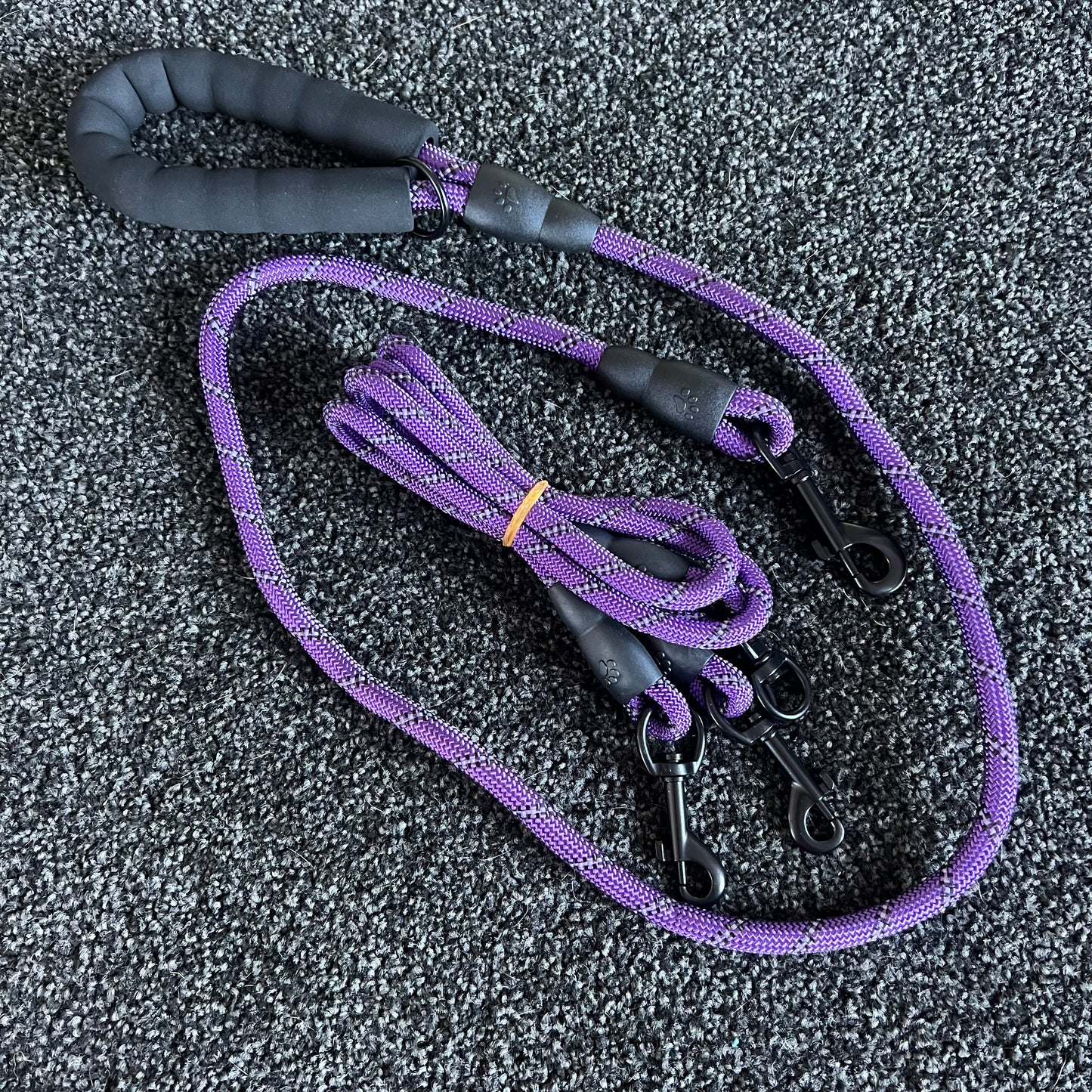 Purple dog leash with black handle on a textured gray surface
