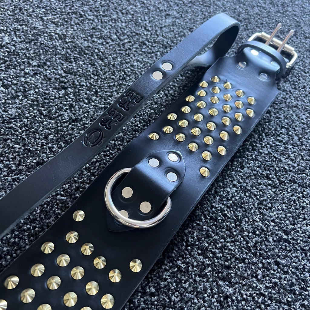 Black leather strap with gold studs on a textured black background