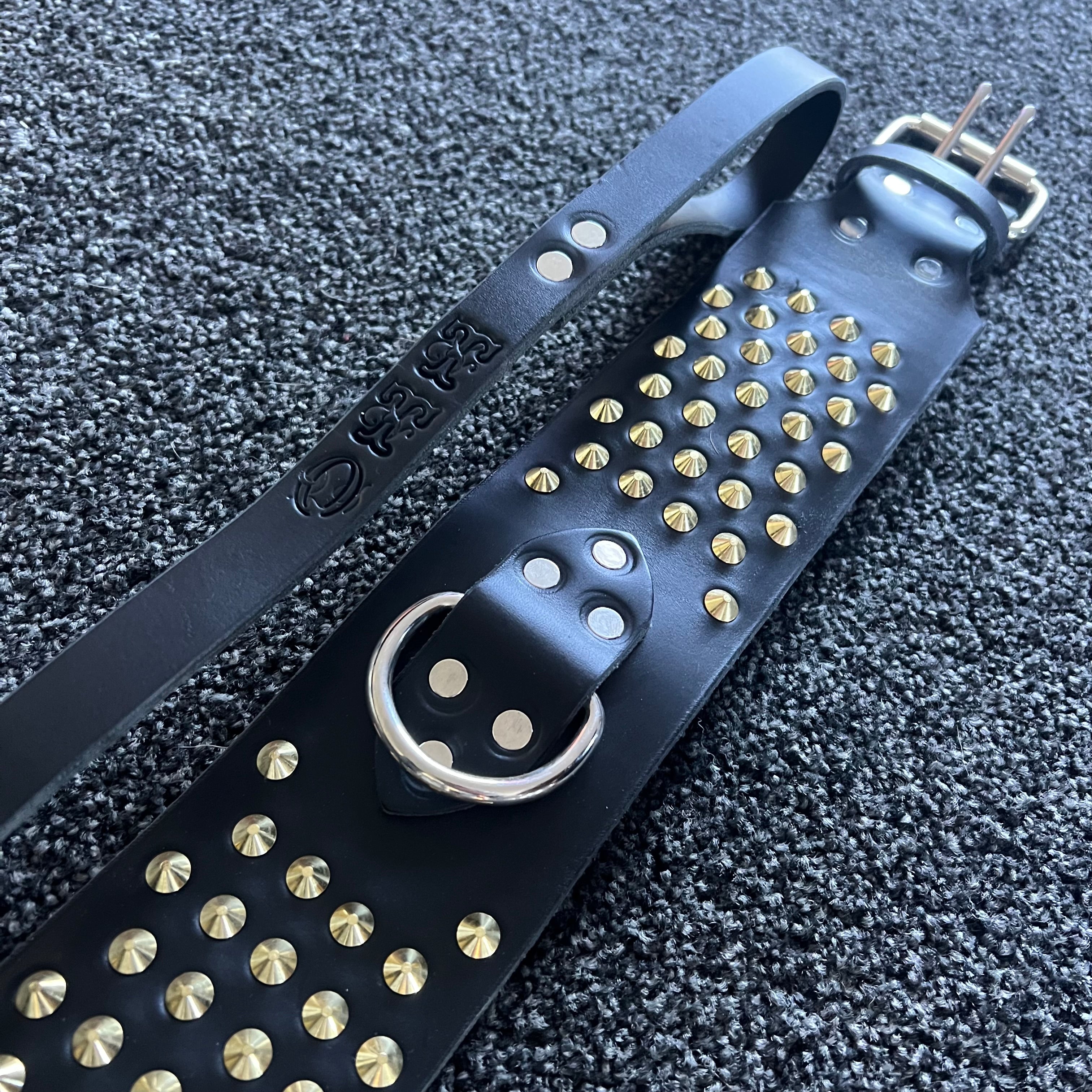 Black leather strap with gold studs on a textured black background