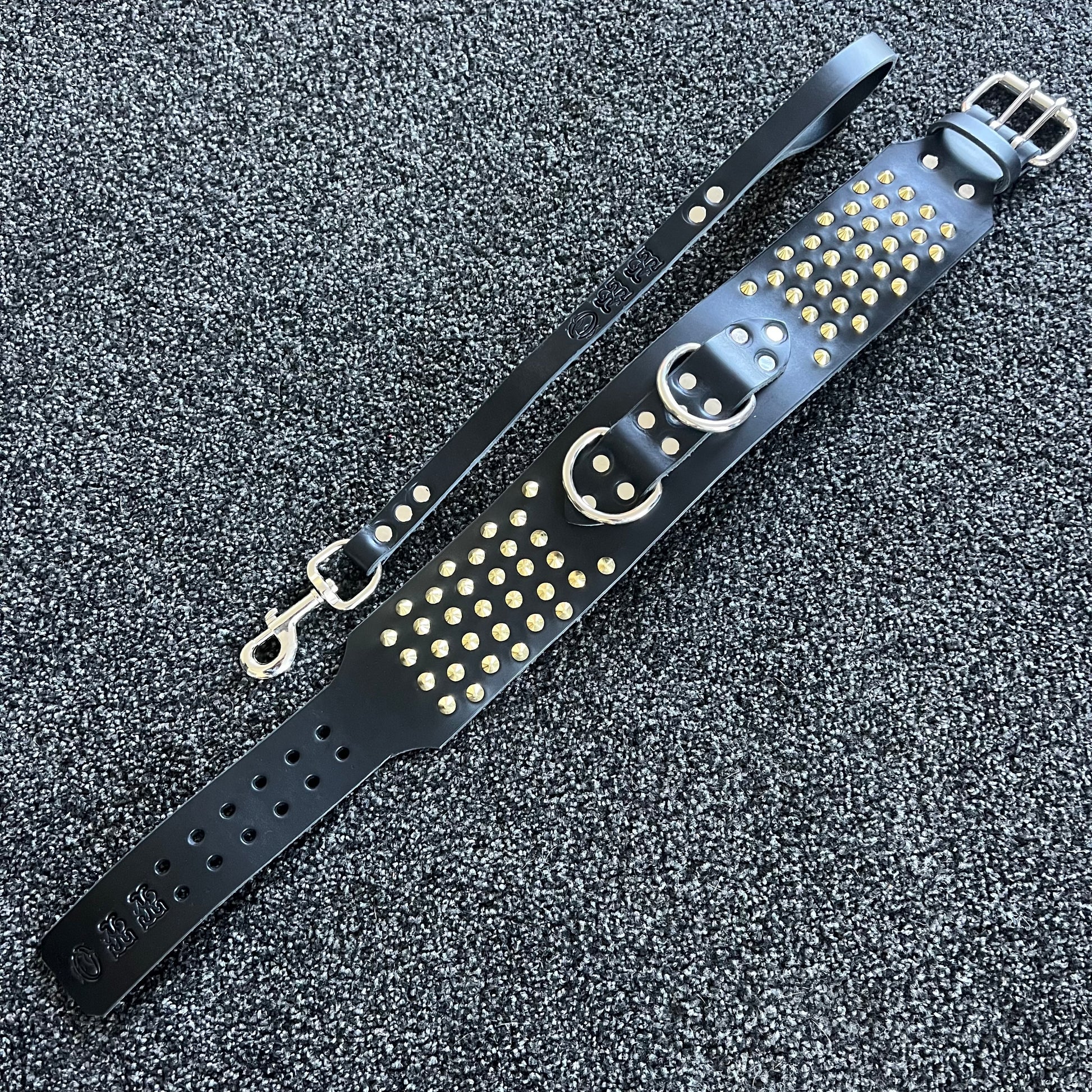Black leather strap with gold studs on a textured gray background