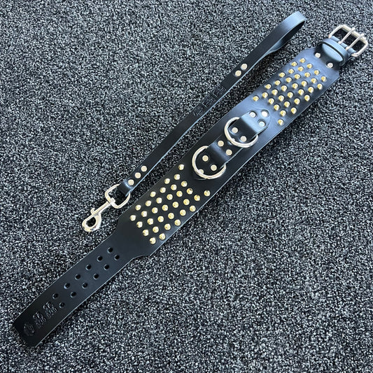 Black leather strap with gold studs on a textured gray background