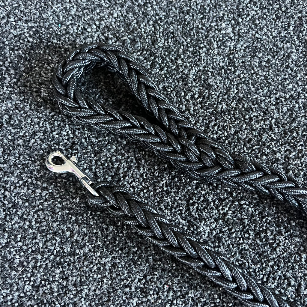 Braided black dog leash on a textured gray surface
