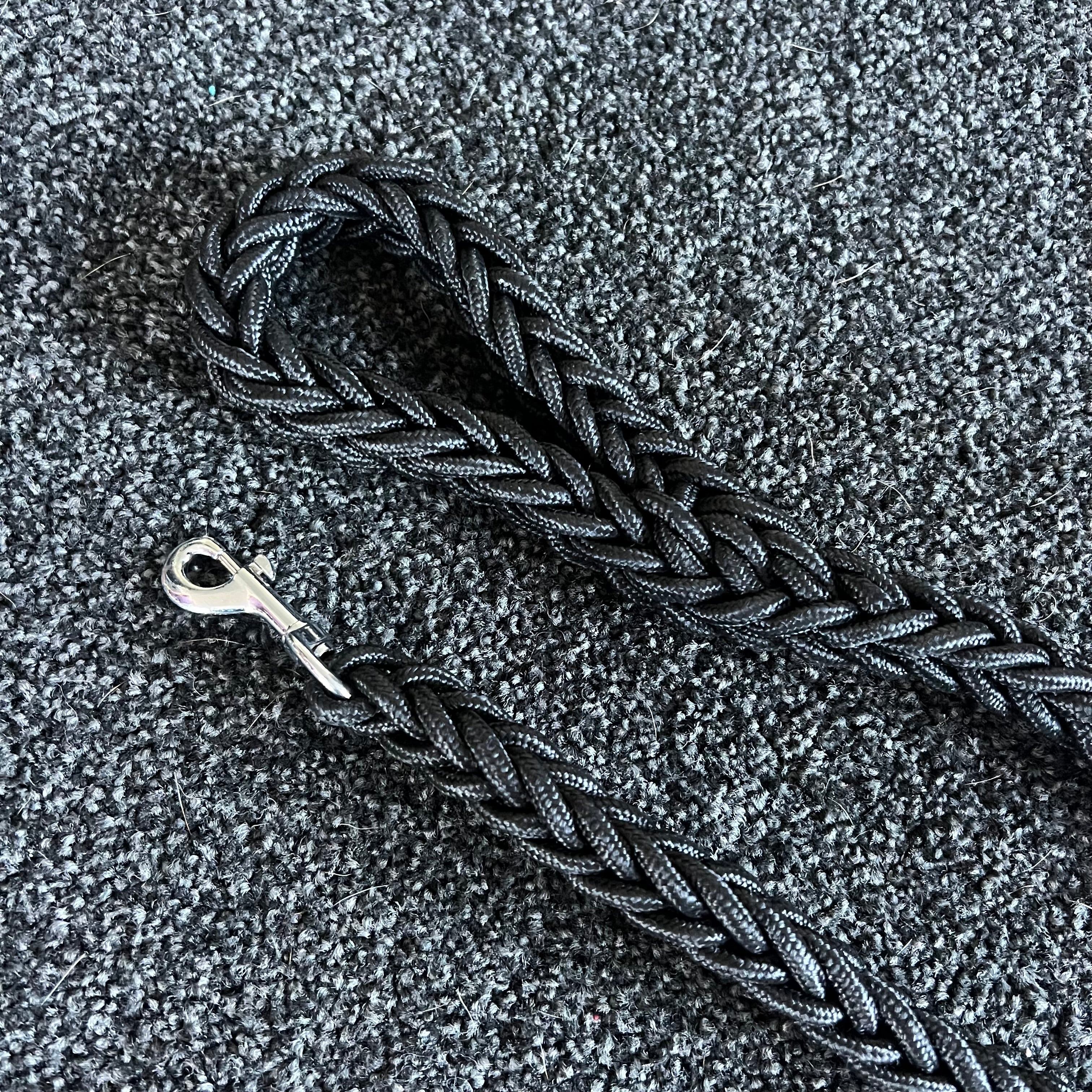 Braided black dog leash on a textured gray surface