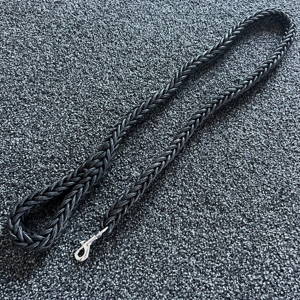 Black braided dog leash on a textured gray surface