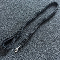 Black braided dog leash on a textured gray surface