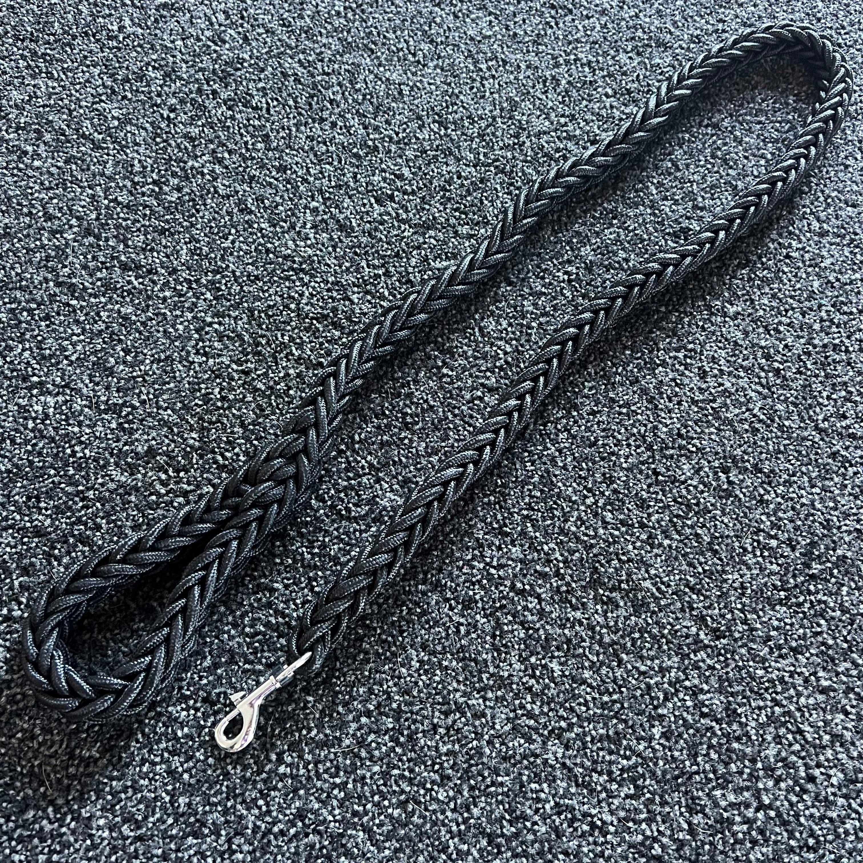 Black braided dog leash on a textured gray surface