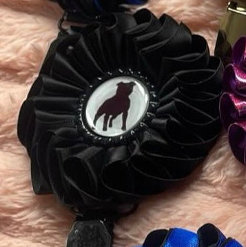 Black decorative item with a central emblem on a pink textured surface