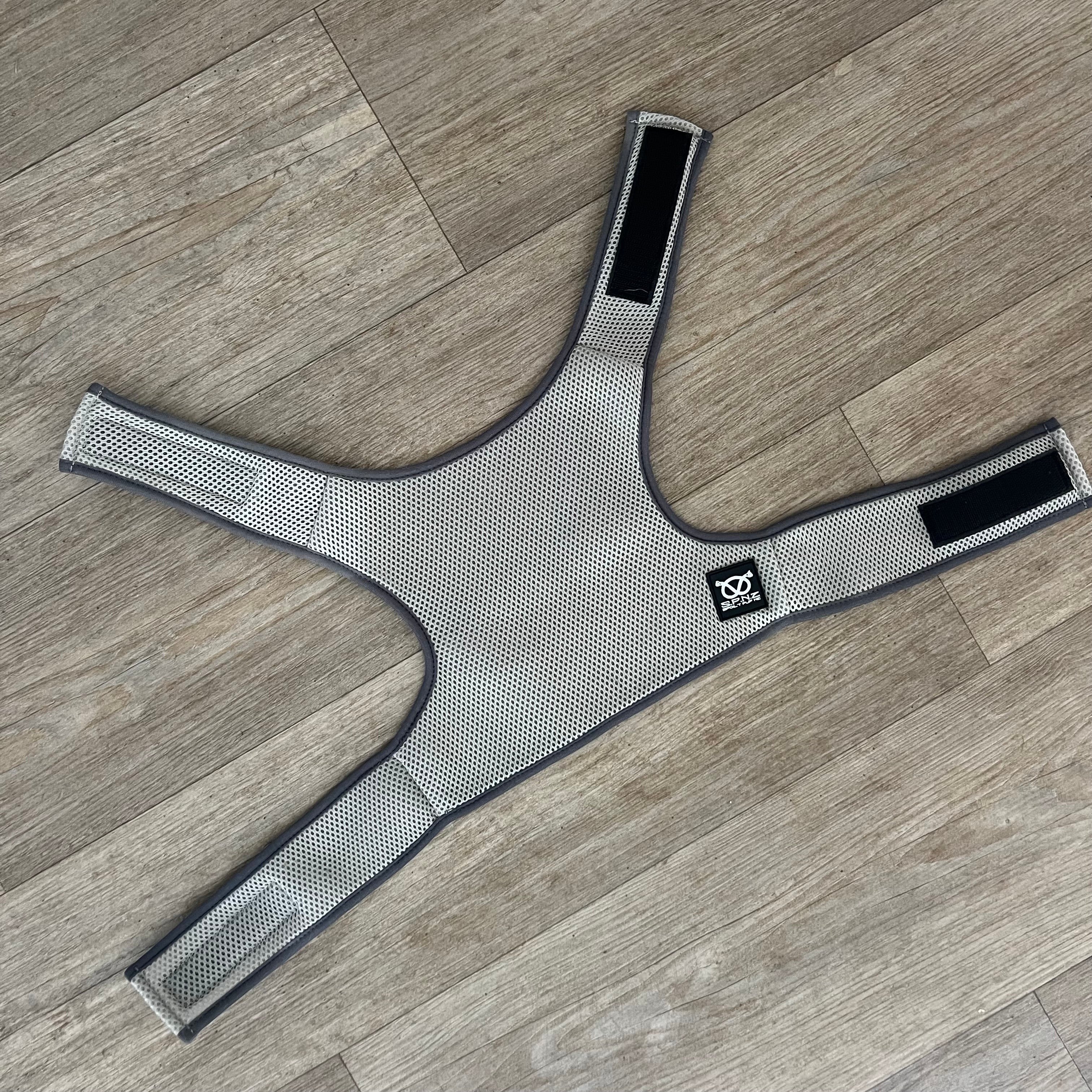 Gray cooling vest with black straps on a wooden floor