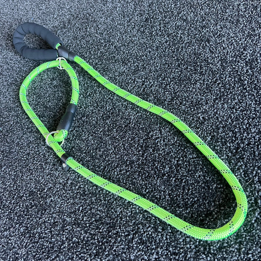 Green dog leash with black handle on a textured gray surface