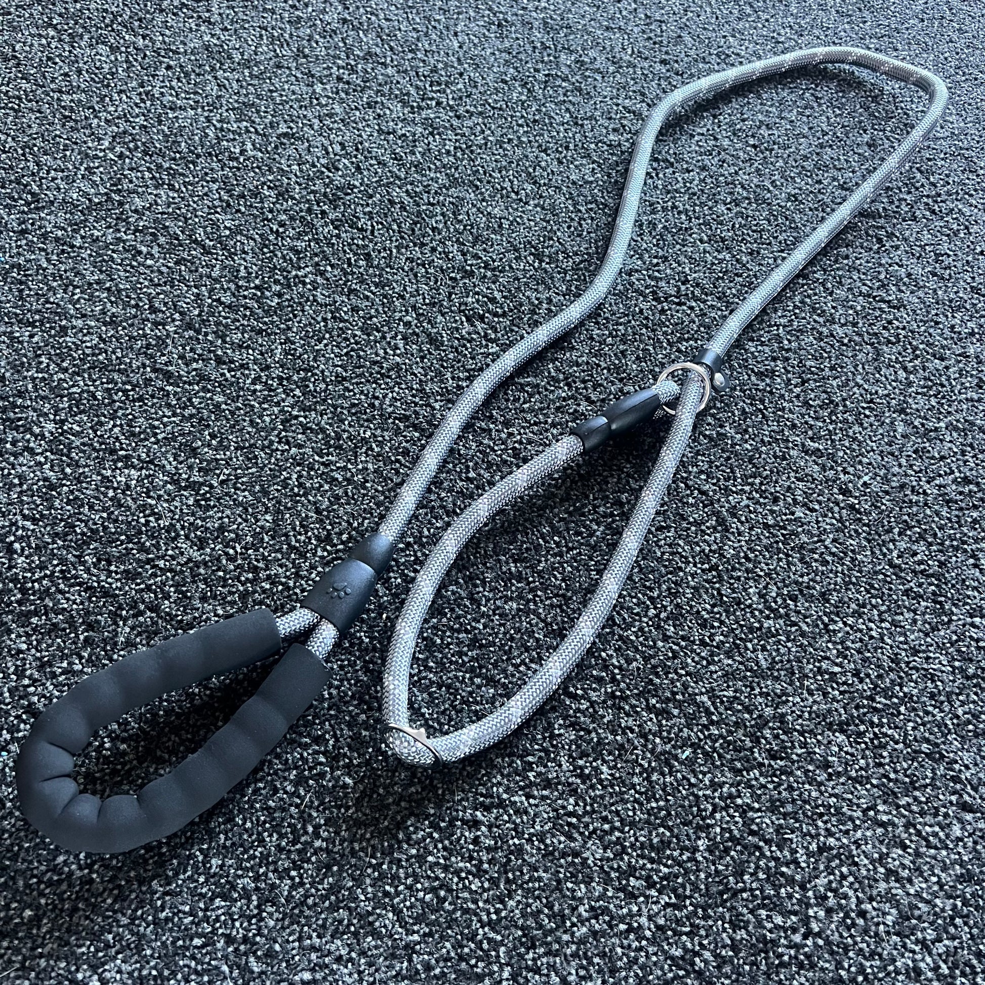 Gray dog leash with black handle on a textured gray surface