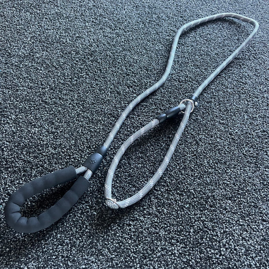 Gray dog leash with black handle on a textured gray surface