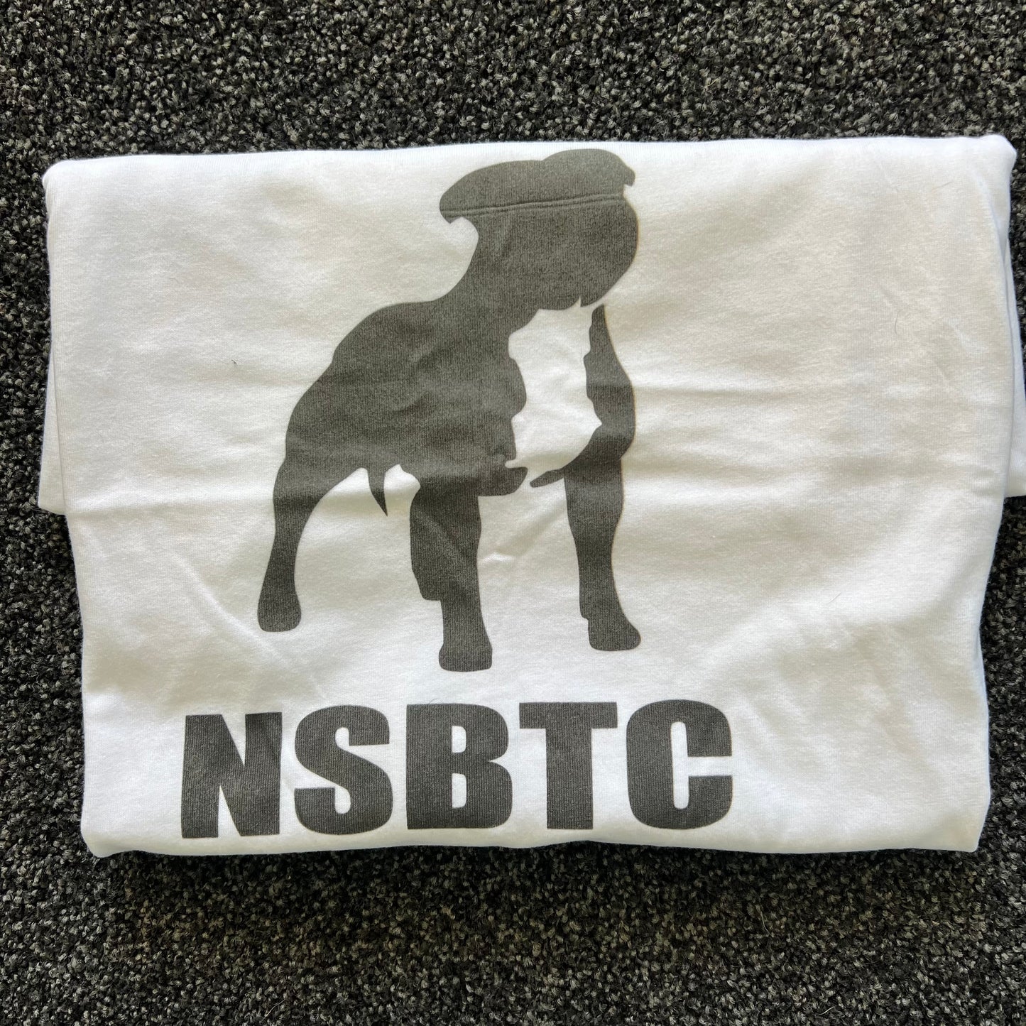 White t-shirt with black graphic and 'NSBTC' text on a textured surface