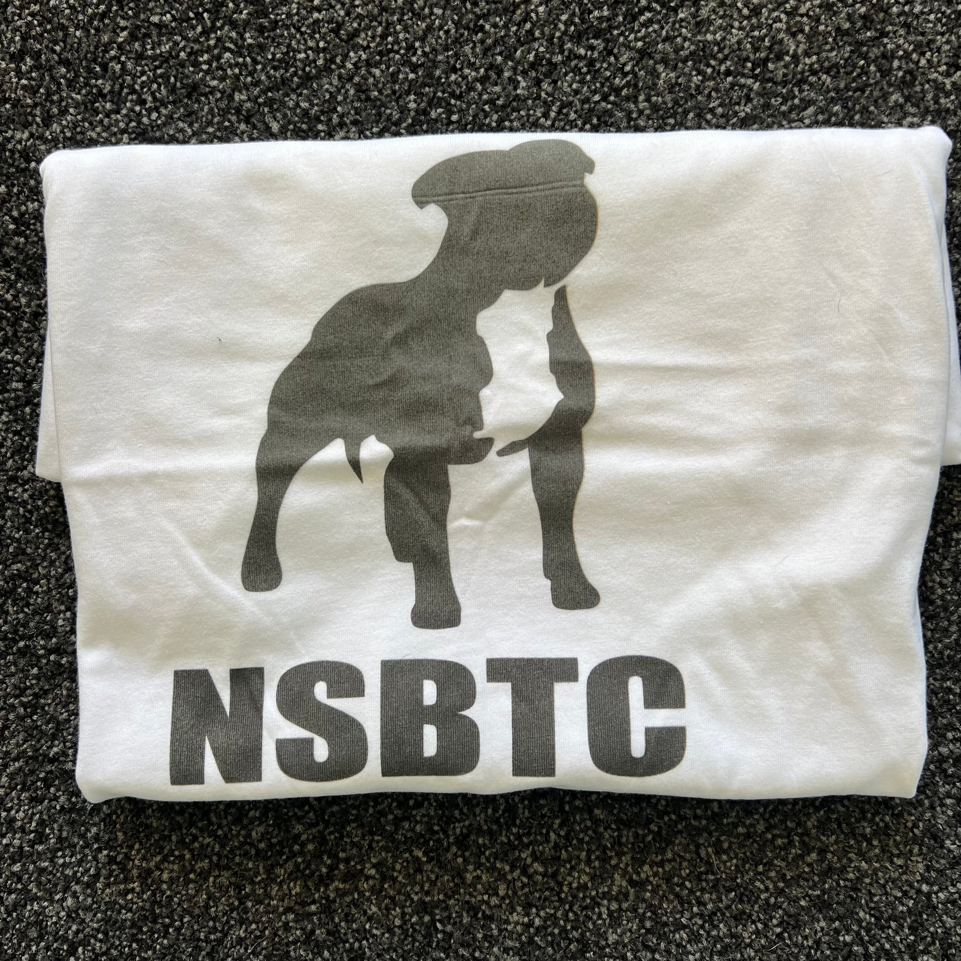 White t-shirt with black graphic and 'NSBTC' text on a textured surface