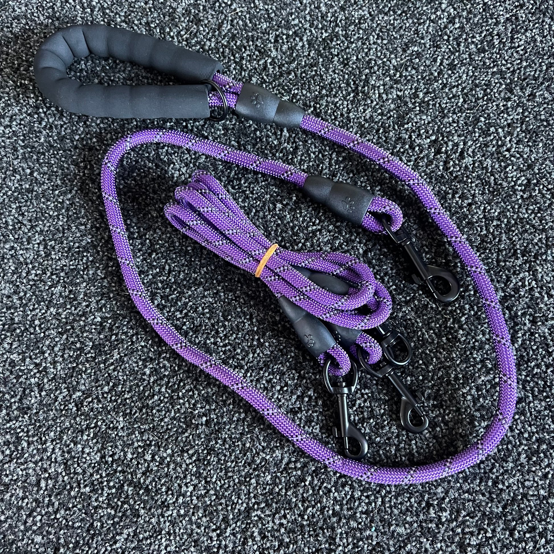 Purple dog leash with black handle on a textured gray surface