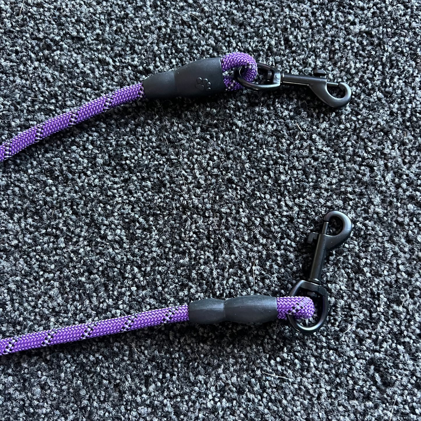 Two purple and black dog leashes on a textured gray surface