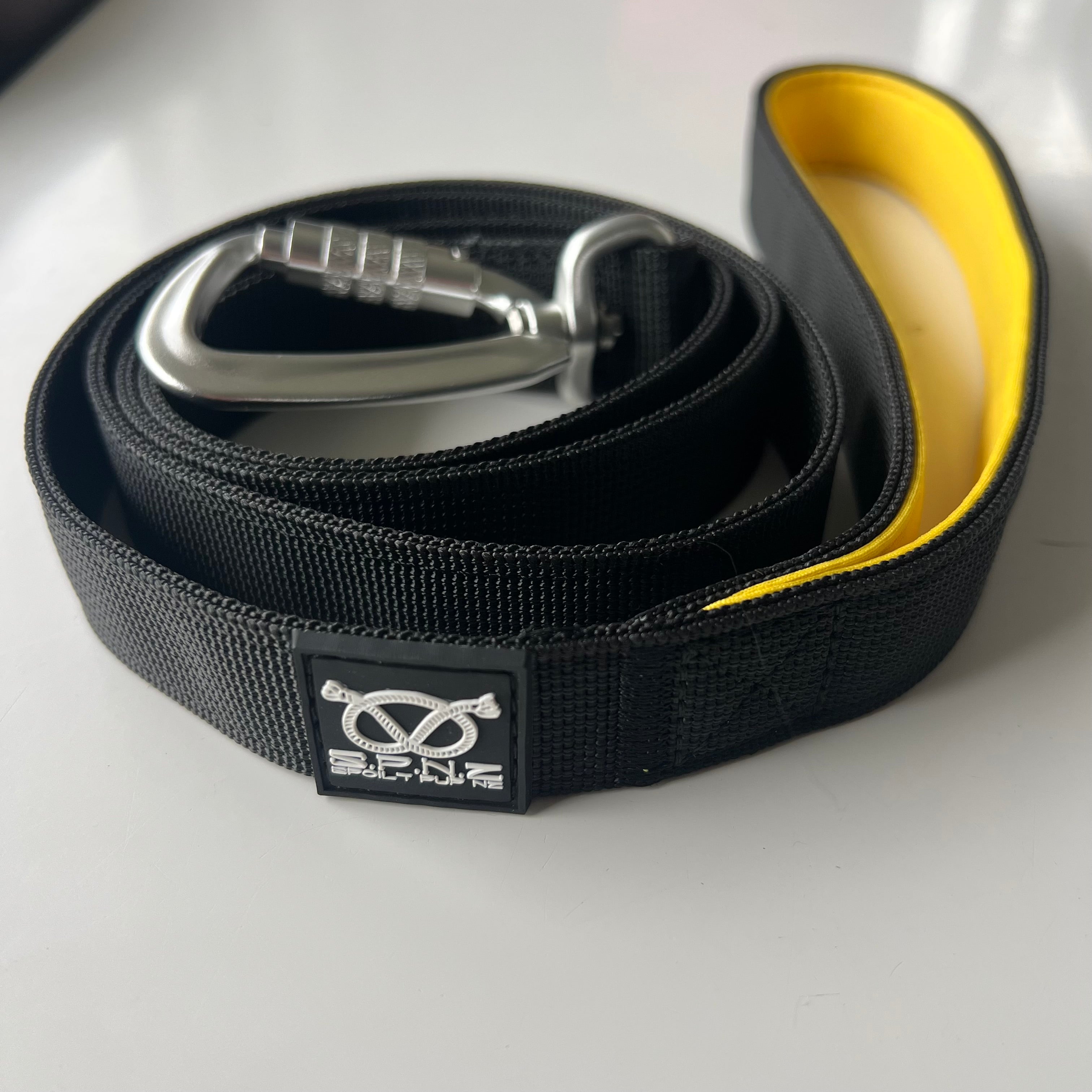 Black leash with yellow interior and silver carabiner on a white background
