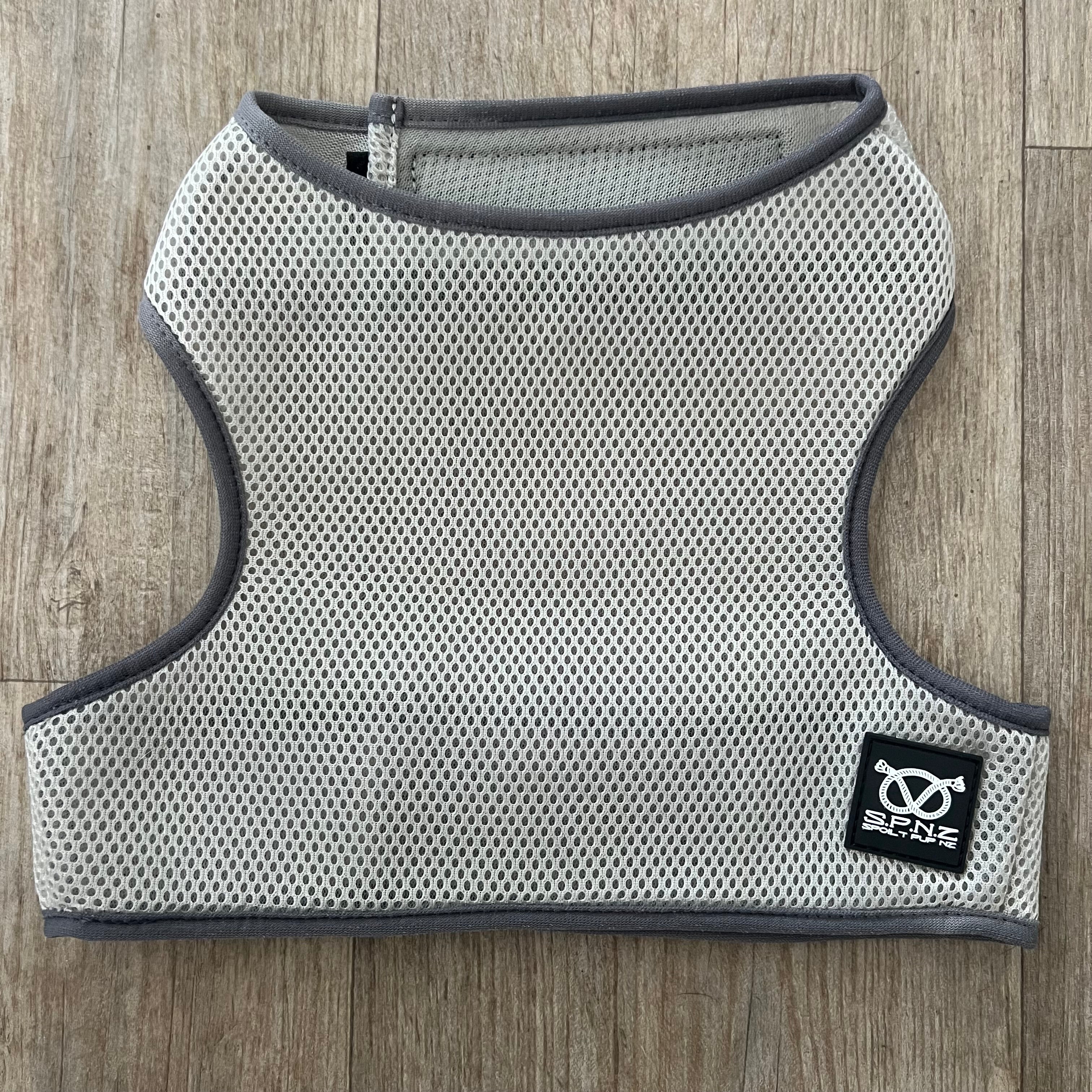 Gray mesh cooling vest with a brand logo on a wooden floor