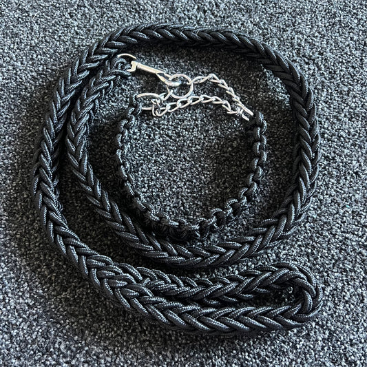 Black braided dog collar with a silver buckle on a textured gray surface